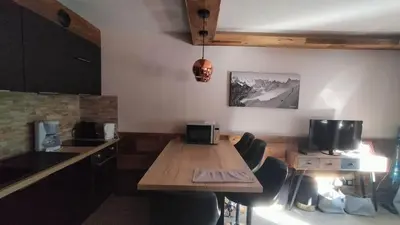 a living room with a table and chairs in a room at Beau studio dans un chalet in Les Houches
