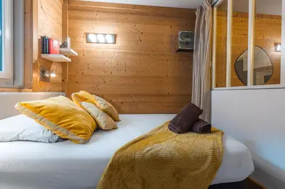 a bedroom with a bed with yellow blankets and pillows at Vue montagne parking privé balcon in Chamonix-Mont-Blanc