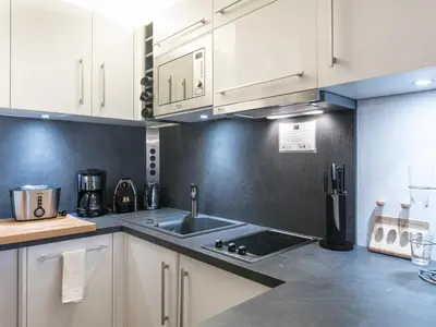 a kitchen with white cabinets and a sink at Vue montagne parking privé balcon in Chamonix-Mont-Blanc
