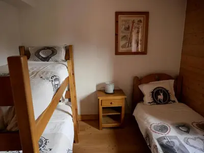 a bedroom with two bunk beds and a night stand at Résidence Les Chardons Argentés in Samoëns