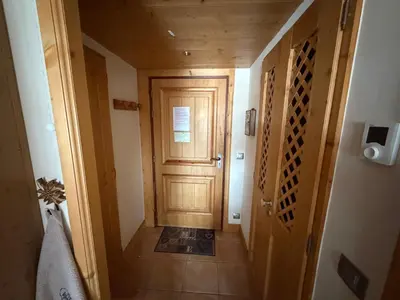 a hallway with a wooden door and a tile floor at Résidence Les Chardons Argentés in Samoëns