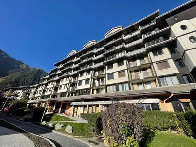 a large apartment building with mountains in the background at Apartment Le Chamois Blanc-8 by Interhome in Chamonix-Mont-Blanc