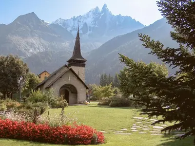 a church in a field with mountains in the background at Studio Champraz-14 by Interhome in Chamonix-Mont-Blanc
