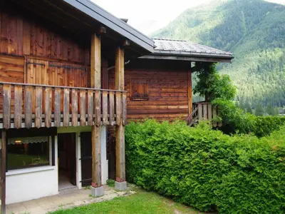 a log cabin with snow covered mountains in the background at Apartment Clos des Outannes-1 by Interhome in Chamonix-Mont-Blanc