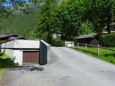 a house with snow covered mountains in the background at Apartment Clos des Outannes-1 by Interhome in Chamonix-Mont-Blanc