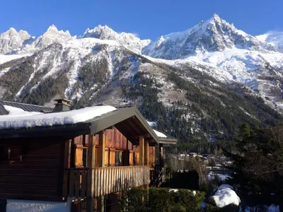 a wooden house in a field with mountains in the background at Apartment Clos des Outannes-1 by Interhome in Chamonix-Mont-Blanc