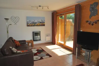 a living room with a couch and a television at Residence Le Pas Au Loup in Samoëns