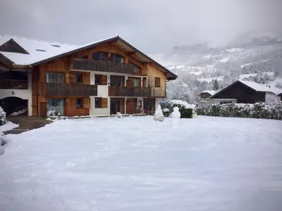 a snow covered yard in front of a house at Residence Le Pas Au Loup in Samoëns