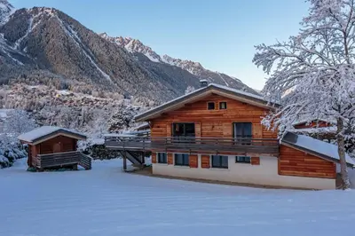 a log cabin in the snow with mountains in the background at Chalet De L'ours - Chamonix All Year in Chamonix-Mont-Blanc