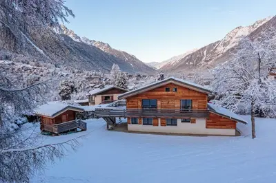 a log cabin in the snow with mountains in the background at Chalet De L'ours - Chamonix All Year in Chamonix-Mont-Blanc
