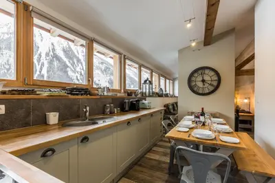 a kitchen with a table and a clock on the wall at Loft Apartment High Rimaye - Mont Blanc Views, Close to Brevent in Chamonix-Mont-Blanc