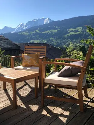 two chairs and a table on a deck with a mountain at Chalet à Megève-Vauvray - Grands Appartements , vue Mont Blanc in Demi-Quartier