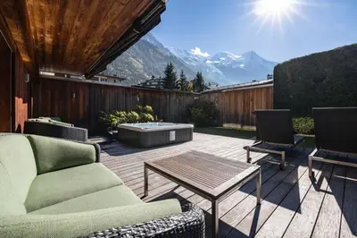 a patio with a table and two chairs and a coffee table at Apartment Au Bon Coin - Luxury Chamonix Hidden Haven, Mont Blanc view, Hot Tub and Garden in Chamonix-Mont-Blanc