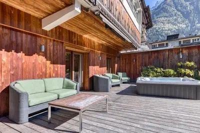a patio with a couch and a table and a tub at Apartment Au Bon Coin - Luxury Chamonix Hidden Haven, Mont Blanc view, Hot Tub and Garden in Chamonix-Mont-Blanc