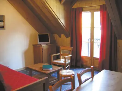 a living room with a table and chairs and a window at Lagrange Vacances Les Arolles in Saint-Gervais-les-Bains