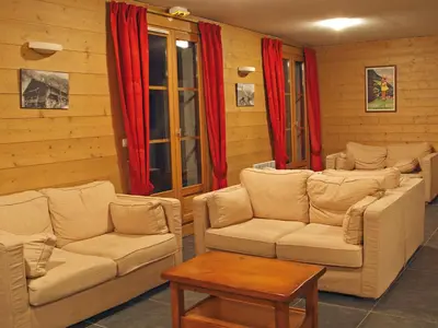 a living room with couches and a table and red curtains at Lagrange Vacances Les Arolles in Saint-Gervais-les-Bains