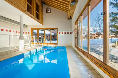 a swimming pool in a house with glass windows at Lagrange Vacances Les Fermes de Samoëns in Samoëns