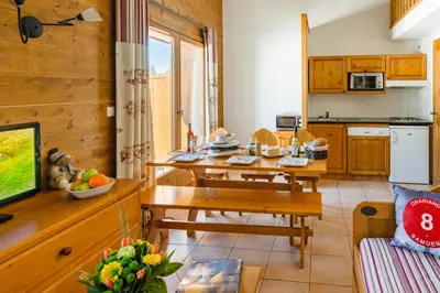 a kitchen and living room with a table and a couch at Lagrange Vacances Les Fermes de Samoëns in Samoëns