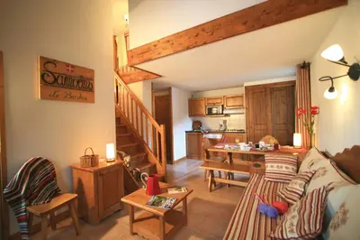 a living room with a couch and a table and a kitchen at Lagrange Vacances Les Fermes de Samoëns in Samoëns