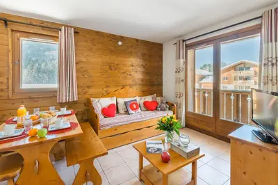 a living room with a couch and a large window at Lagrange Vacances Les Fermes de Samoëns in Samoëns