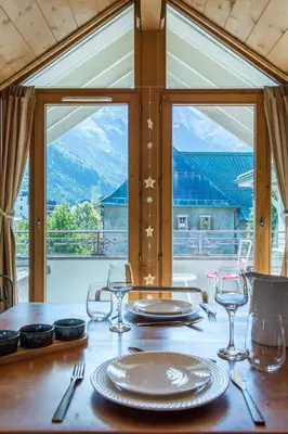 a table with plates and glasses on a table with a window at Villa Vallet Apartment - Chamonix All Year in Chamonix-Mont-Blanc