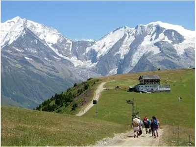 a group of people walking down a dirt road on a mountain at megeve appartement des Crêtets in Megève