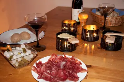 a table with a plate of food and a glass of wine at Appartement Les Arolles in Chamonix-Mont-Blanc