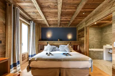 a bedroom with a large bed with wooden ceilings at Au Coin Du Feu in Megève