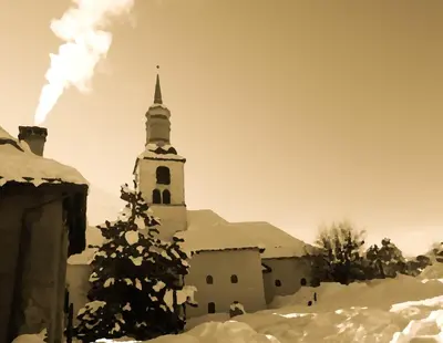 an old church with a steeple in the snow at Hotel Du Clocher in Chamonix-Mont-Blanc