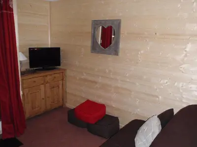 a living room with a television and a red ottoman at Hôtel Rent in Megève