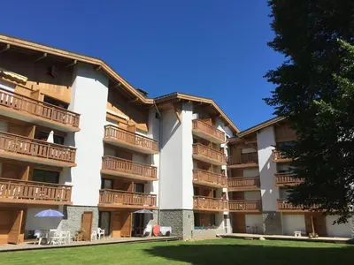 an apartment building with balconies and a lawn at Hôtel Rent in Megève