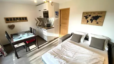 a bedroom with a bed and a desk and a kitchen at Hôtel Rent in Megève