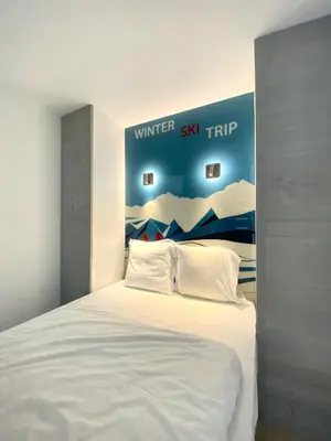 a bedroom with a white bed with a poster on the wall at Hôtel Rent in Megève