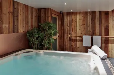 a bathroom with a large tub with wooden walls at Le Saint Antoine in Les Houches