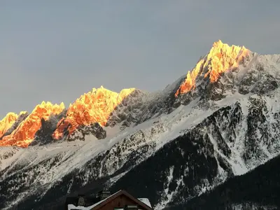a snow covered mountain with sun shining on it at Le Saint Antoine in Les Houches