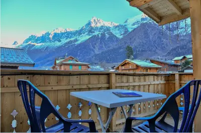 a table and two chairs on a balcony with mountains at Le Saint Antoine in Les Houches