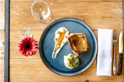 a blue plate with a piece of food and a flower at Hôtel Les Roches Fleuries in Cordon