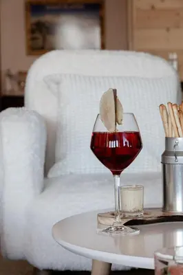 a glass of wine on a table next to a couch at Hôtel Les Roches Fleuries in Cordon