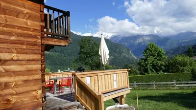 a deck with a table and a white umbrella at Chamonix petit chalet Cocooning in Servoz