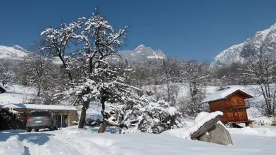 a snow covered house with a car parked next to a tree at Chamonix petit chalet Cocooning in Servoz
