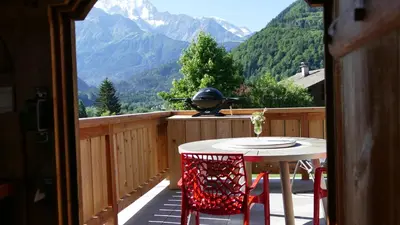 a table and chairs on a balcony with a grill at Chamonix petit chalet Cocooning in Servoz