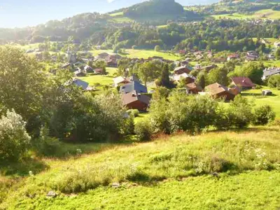 a small village on a hill with green grass and trees at Chalet spacieux à Cordon 180 m² avec vue montagne in Cordon