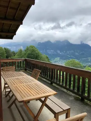 a wooden table and chairs on a balcony with a view at Chalet spacieux à Cordon 180 m² avec vue montagne in Cordon