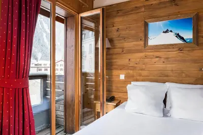 a pink building with snow covered mountains in the background at Hôtel Vallée Blanche in Chamonix-Mont-Blanc