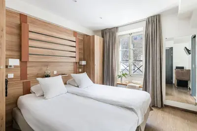a bedroom with two beds and a large window at Hôtel Vallée Blanche in Chamonix-Mont-Blanc
