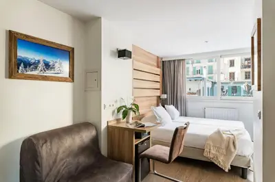 a hotel room with a bed and a chair at Hôtel Vallée Blanche in Chamonix-Mont-Blanc
