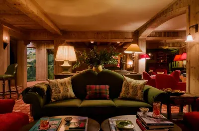 a living room with a green couch and red chairs at Hôtel Saint-Georges Relais & Châteaux in Megève