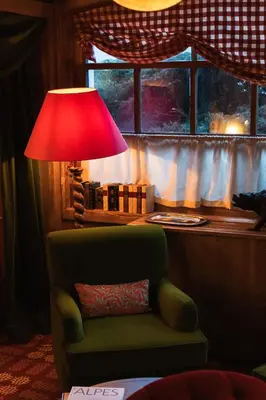a lamp sitting next to a chair with a red lamp shade at Hôtel Saint-Georges Relais & Châteaux in Megève