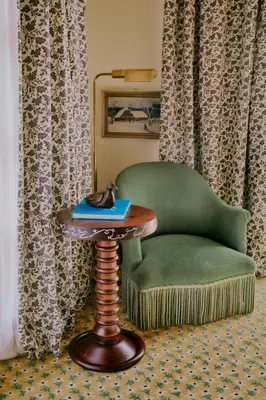 a green chair and a table with a cat on a book at Hôtel Saint-Georges Relais & Châteaux in Megève