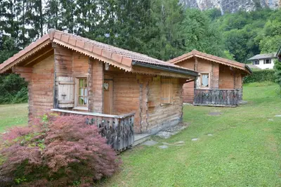 two small wooden houses in a field with a yard at Le Relais Du Mont Blanc in Magland